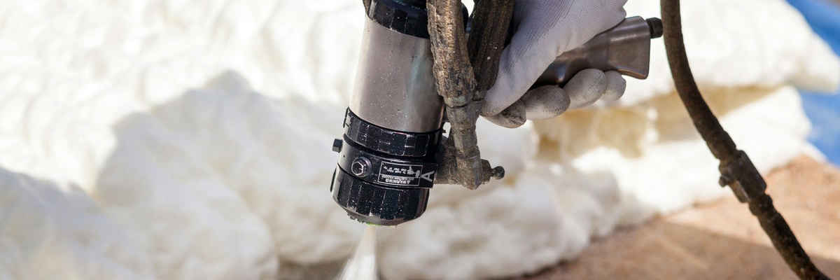 Technician spraying foam insulation using plural component spray gun